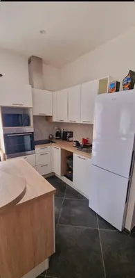 a kitchen with white cabinets and a white refrigerator at Maison Vacance Proche De Calvi in Calenzana