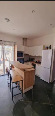 a kitchen with a table and a white refrigerator at Maison Vacance Proche De Calvi in Calenzana