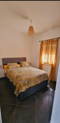 a bedroom with a bed with a comforter and a window at Maison Vacance Proche De Calvi in Calenzana