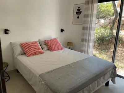 a bedroom with a bed with two red pillows on it at Corse - Maison face à la mer in Serra-di-Ferro
