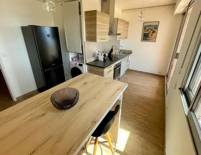 a kitchen with a wooden table and a refrigerator at VUE EXCEPTIONNELLE - Ajaccio T3 rte Sanguinaires - Santa Lina in Ajaccio