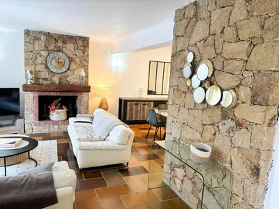 a living room with a couch and a stone wall at Villa NAOMI piscine à 100 m de la plage in Olmeto