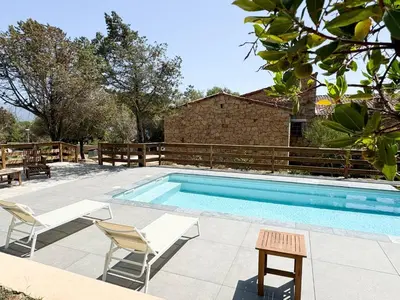 a swimming pool with two chairs and a table at Villa NAOMI piscine à 100 m de la plage in Olmeto