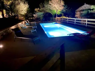 a swimming pool at night with chairs around it at Villa NAOMI piscine à 100 m de la plage in Olmeto