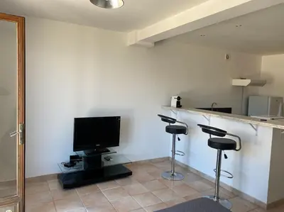 a room with a bar with two stools and a television at Studio équipé vue mer in Propriano
