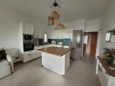 a kitchen with white cabinets and a wooden counter top at Le petit Sampiero 2 in Pietrosella