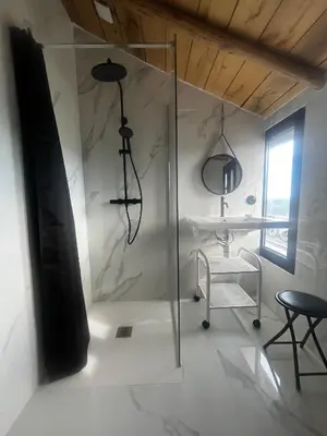 a glass shower in a room with a table and a chair at A Scontra in Moïta