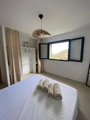 a bedroom with two towels on a bed with a window at Grande maison à Belgodère Balagne in Belgodère