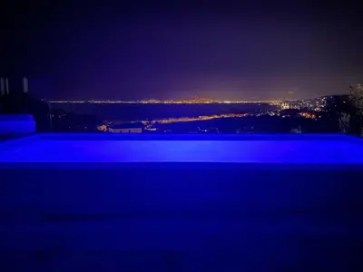 a swimming pool at night with a view of the city at Villa vue mer piscine in Pietrosella