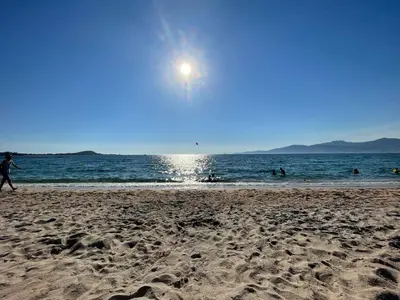 a person walking on a beach with the sun in the sky at Villa vue mer piscine in Pietrosella