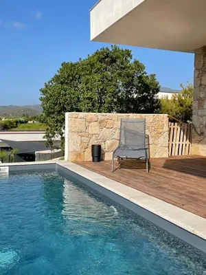 a chair sitting on a deck next to a swimming pool at Villa vue mer piscine in Pietrosella