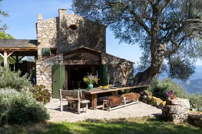 a stone house with a picnic table and a tree at Magnifique Bergerie AMORE vue panoramique mer et montagne in Cargèse