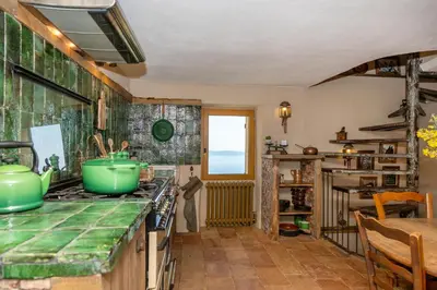 a kitchen with a green counter top and a table at Magnifique Bergerie AMORE vue panoramique mer et montagne in Cargèse