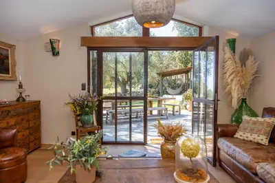 a living room with a glass door leading to a patio at Magnifique Bergerie AMORE vue panoramique mer et montagne in Cargèse