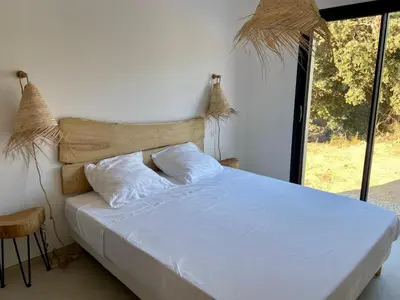 a bedroom with a white bed with a large window at Casa Serena Plage de Lozari 5 kilomètres Ile Rousse 12 kilomètres in Occhiatana