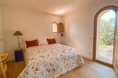 a bedroom with a bed and a large window at Villa A Muvra Di Pinarellu in Pinarellu
