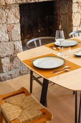 a wooden table with plates and wine glasses on it at Villa A Muvra Di Pinarellu in Pinarellu