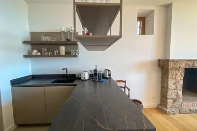 a kitchen with a black counter top and a fireplace at Villa A Muvra Di Pinarellu in Pinarellu