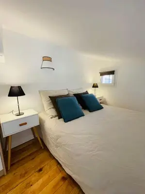 a bedroom with a white bed with two blue pillows at Mini villa agosta plage in Albitreccia