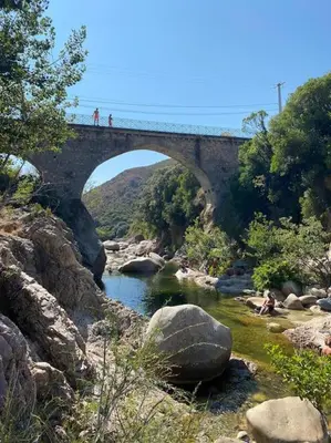 a bridge over a river with people walking on it at Mini villa agosta plage in Albitreccia