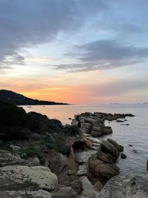a group of rocks in the water at sunset at Mini villa agosta plage in Albitreccia
