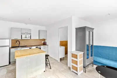 a kitchen with white cabinets and a blue couch at Villa Mara in Lecci