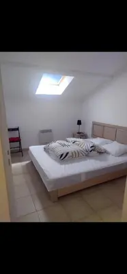 a bedroom with a large bed with a skylight at Appartement Corse in Santa-Maria-Poggio