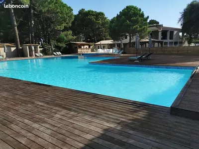 a large blue swimming pool with a wooden deck at Corse du sud Fiori di cala rossa T2 rez de jardin dans résidence piscine in Lecci
