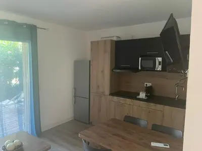 a kitchen with a table and a microwave and a table and chairs at Corse du sud Fiori di cala rossa T2 rez de jardin dans résidence piscine in Lecci