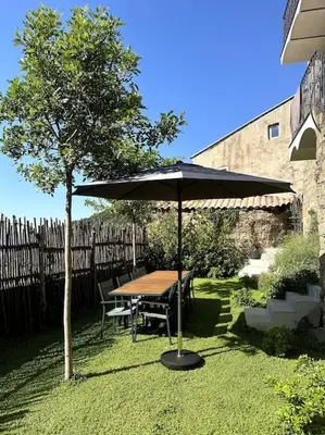 a table with an umbrella next to a tree at Charming air-conditioned house with garden & view in Olmeto