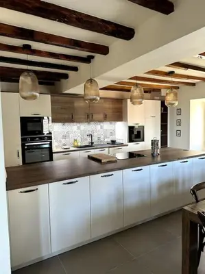 a large kitchen with white cabinets and appliances at Charming air-conditioned house with garden & view in Olmeto