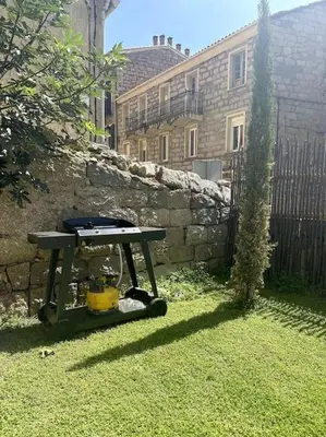 a picnic table in a yard next to a stone wall at Charming air-conditioned house with garden & view in Olmeto