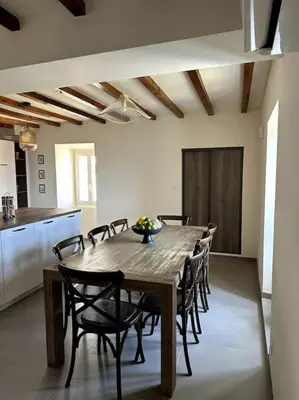 a dining room with a wooden table and chairs at Charming air-conditioned house with garden & view in Olmeto