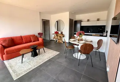 a living room with a red couch and a table at À Casetta Porticcio Spacieux T2 50m2 Neuf Terrasse & Jardin privatif à 3min des plus belles plages in Porticcio