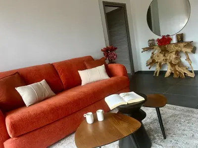 a living room with a red couch and a table at À Casetta Porticcio Spacieux T2 50m2 Neuf Terrasse & Jardin privatif à 3min des plus belles plages in Porticcio
