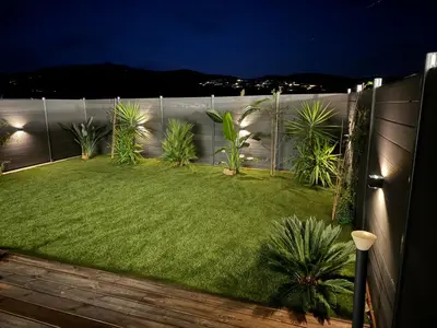 a backyard with a fence and a lawn with plants at À Casetta Porticcio Spacieux T2 50m2 Neuf Terrasse & Jardin privatif à 3min des plus belles plages in Porticcio