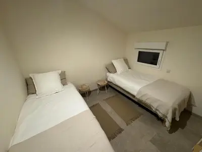 a room with two beds and a tv on the wall at Charmante maison en pierre vue mer et piscine privée in Cuttoli-Corticchiato