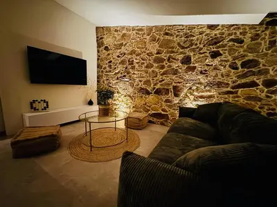 a living room with a couch and a stone wall at Charmante maison en pierre vue mer et piscine privée in Cuttoli-Corticchiato