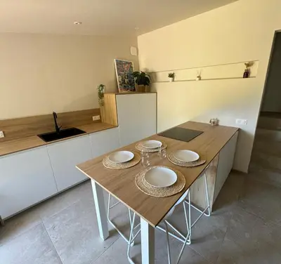 a kitchen with a wooden table with plates on it at Charmante maison en pierre vue mer et piscine privée in Cuttoli-Corticchiato