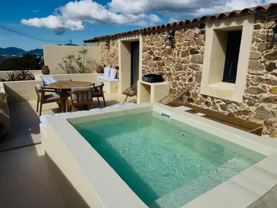 a swimming pool in front of a house at Charmante maison en pierre vue mer et piscine privée in Cuttoli-Corticchiato