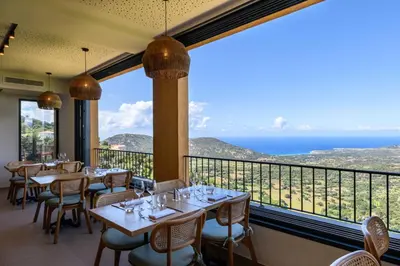 a restaurant with tables and chairs and a view of the ocean at Le Belvedere in Lavatoggio