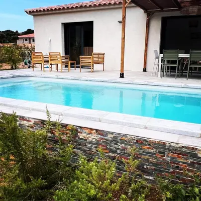 a swimming pool with chairs and a table and a house at Casa Corsu Villa avec piscine in Figari