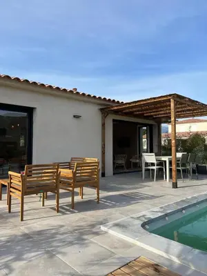 a patio with benches and a table and a pool at Casa Corsu Villa avec piscine in Figari