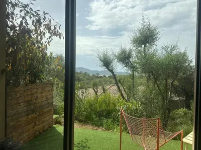 a window view of a garden with a hammock at Casaty Mare in Porto-Vecchio