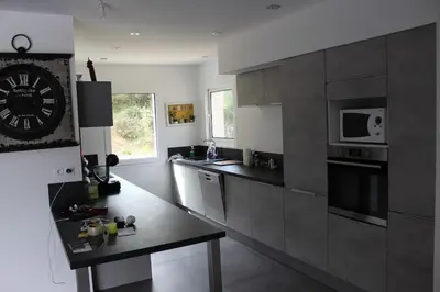 a kitchen with stainless steel appliances and a clock on the wall at Villa ALPANNA in Cirendinu