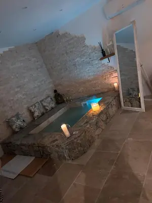 a swimming pool in a room with a stone wall at I pozzi jacuzzi furiani love room haute corse in Furiani