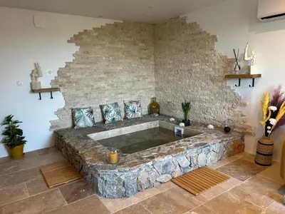 a bath tub in a room with a stone wall at I pozzi jacuzzi furiani love room haute corse in Furiani