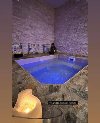 a large pool in a room with a brick wall at I pozzi jacuzzi furiani love room haute corse in Furiani