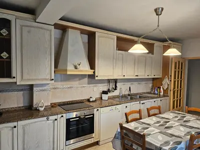 a kitchen with white cabinets and a table in it at Villa des fleurs in Ortale