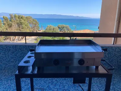 a grill on a balcony with a view of the ocean at Duplex terrasse vue mer in Pisinale